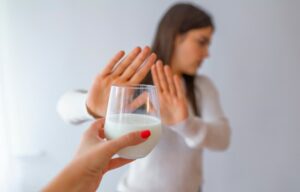 Persona rechazando un vaso de leche, simbolizando la intolerancia a la lactosa o una dieta sin lácteos