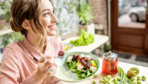 Mujer disfrutando de una ensalada fresca con ingredientes naturales, simbolizando una alimentación saludable, inclusiva y llena de sabor.